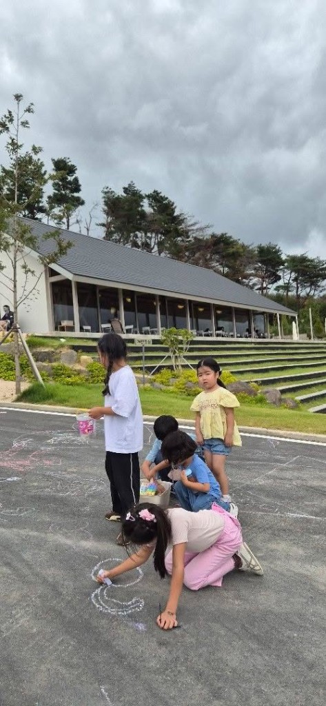 Children drawing with chalk on pavement outside Dayul Soop cafe