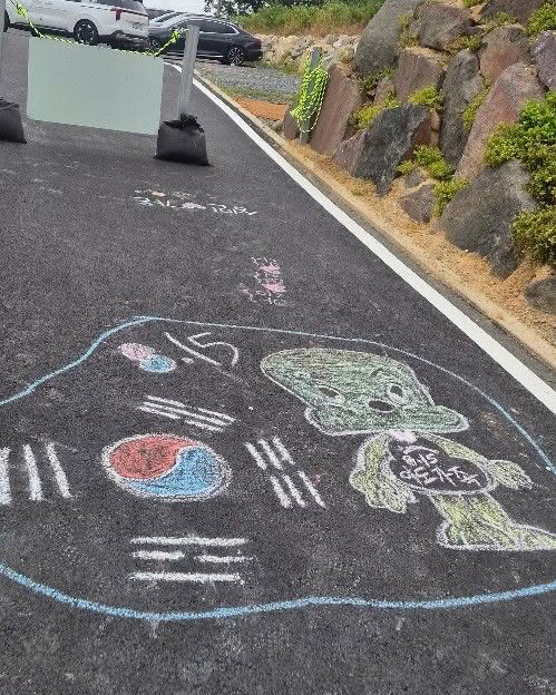 Chalk drawing of Korean flag and character on asphalt