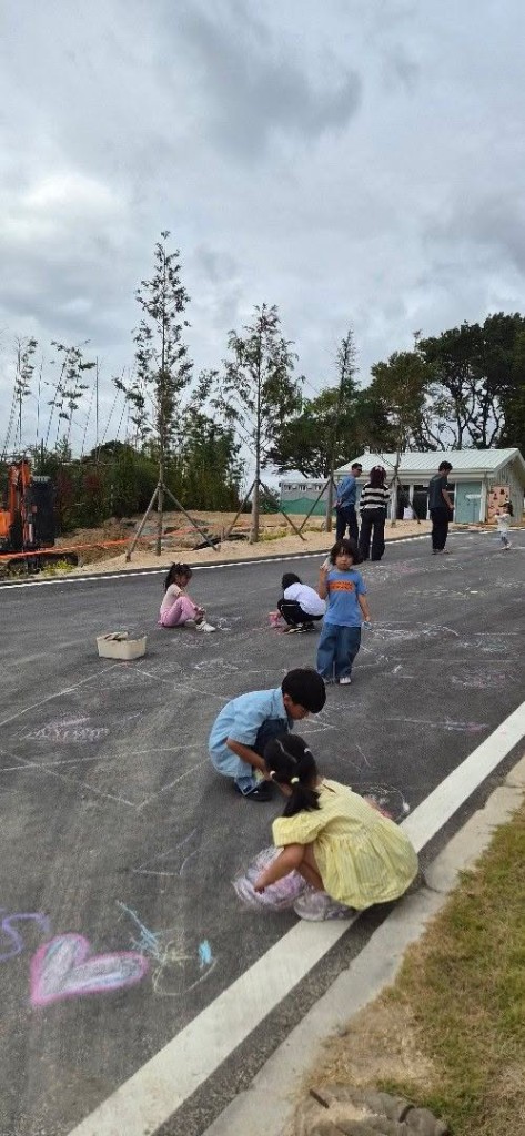 Children drawing with chalk on asphalt with heart doodle in the foreground