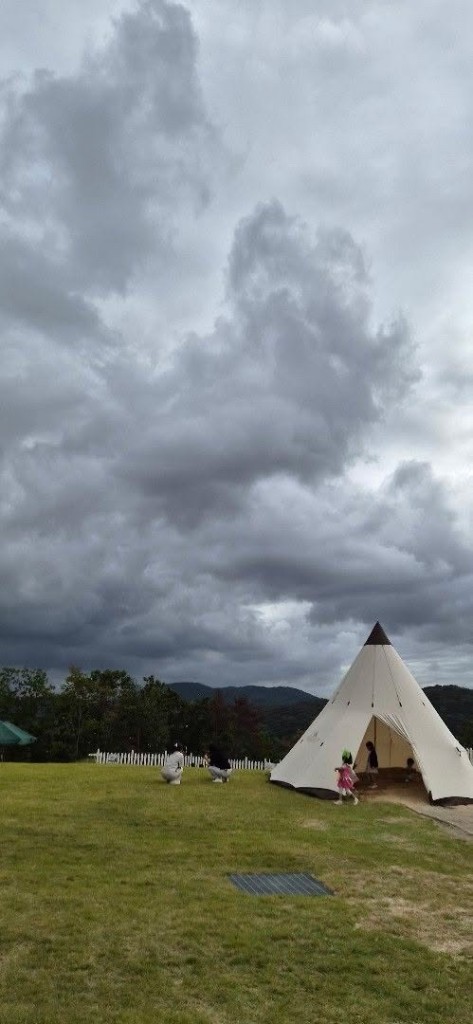 White teepee tent on a grassy field with children nearby