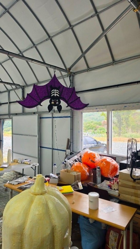 Purple glitter bat hanging above Halloween pumpkin props