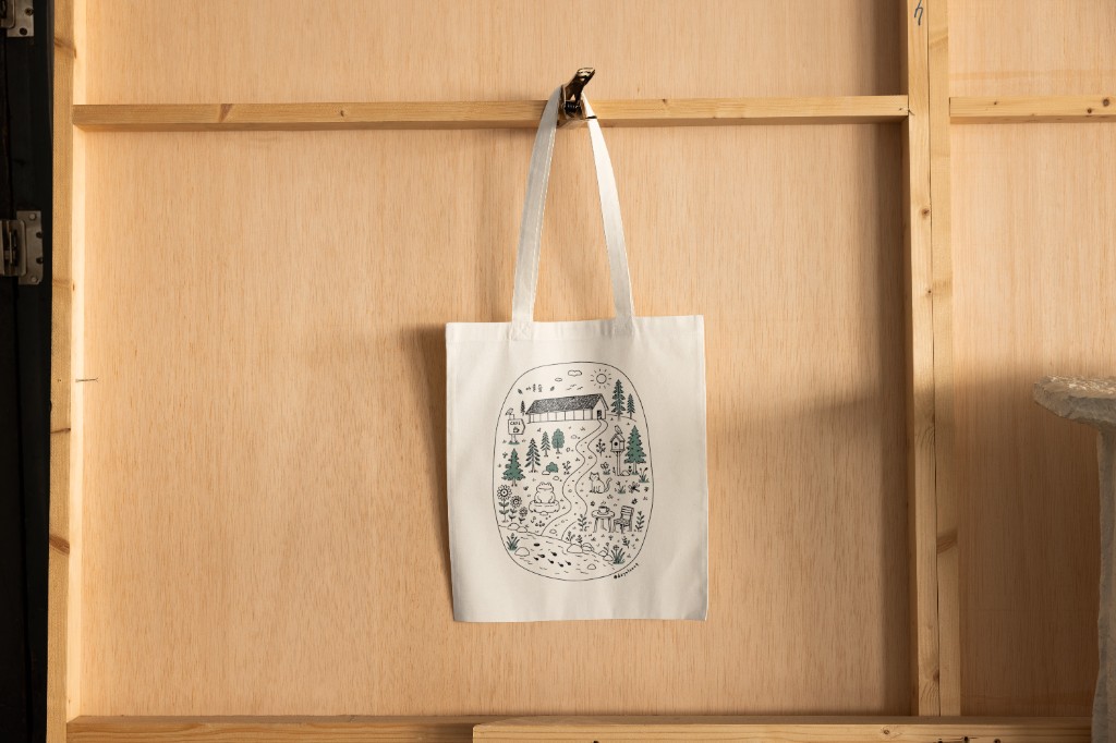 Dayul Soop Cafe tote bag with forest cafe doodle hanging against wood paneling