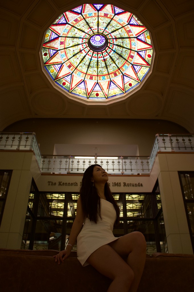 Person looking up at a stained-glass rotunda ceiling