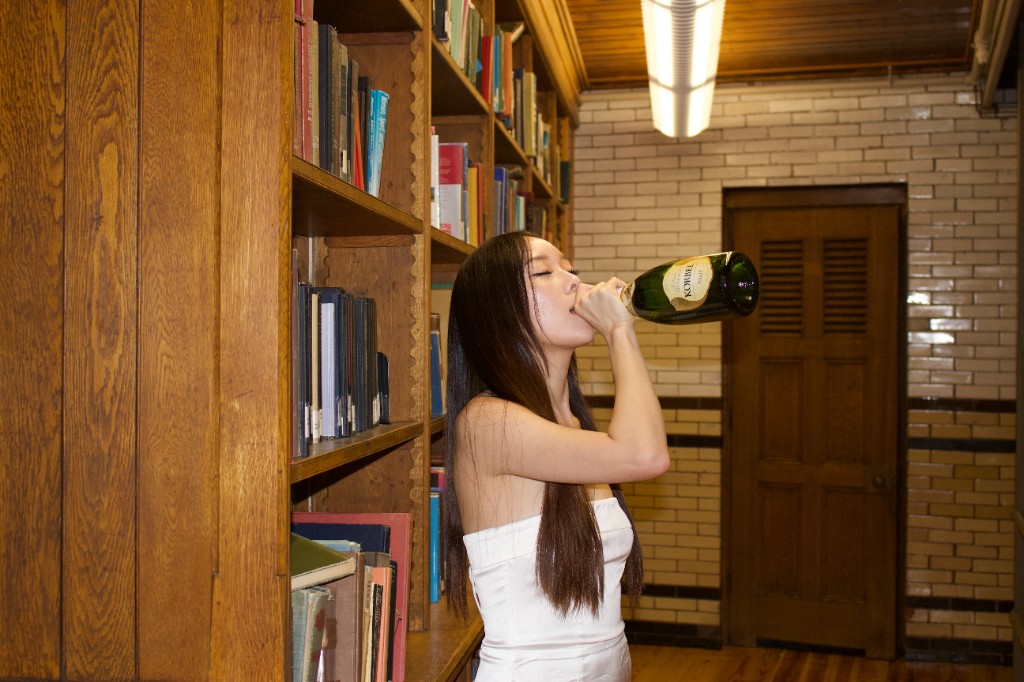 Person in a library drinking from a bottle