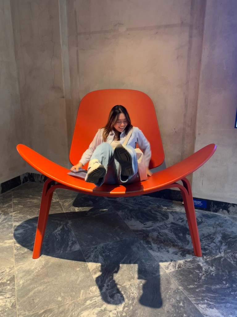 Sitting in an oversized orange lounge chair at a Copenhagen design exhibition