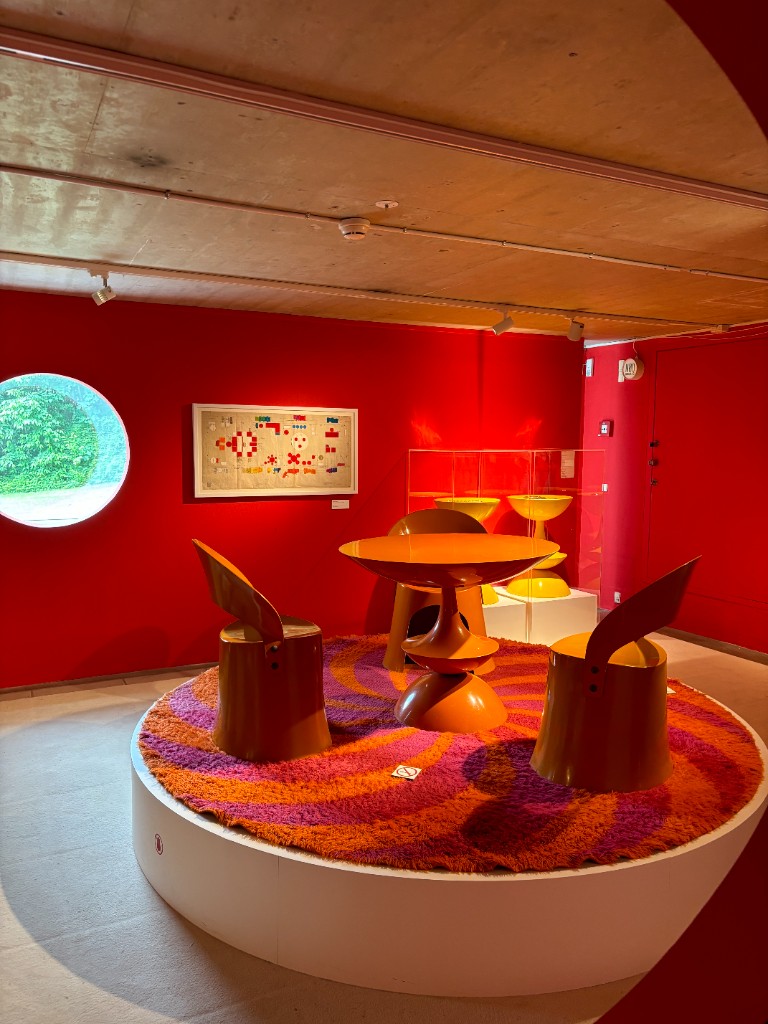 Orange molded dining set in a red-walled design room